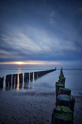 Breakwaters on beach, Netherlands, Zeeland, Domburg. The sun is setting and the is a storm coming