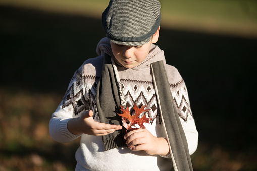 A little boy is playing outdoors during a winter storm. He is smiling while looking at the camera.