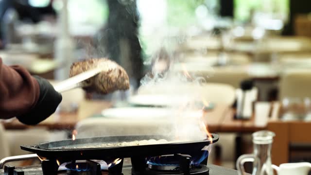 Chef cooks tenderloin on a hot skillet in a restaurant