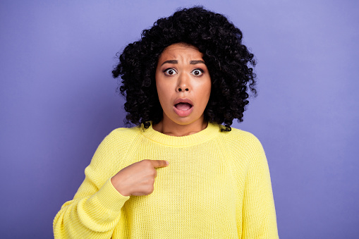 Photo of offended astonished woman with afro hairdo dressed yellow sweater directing at herself isolated on violet color background.