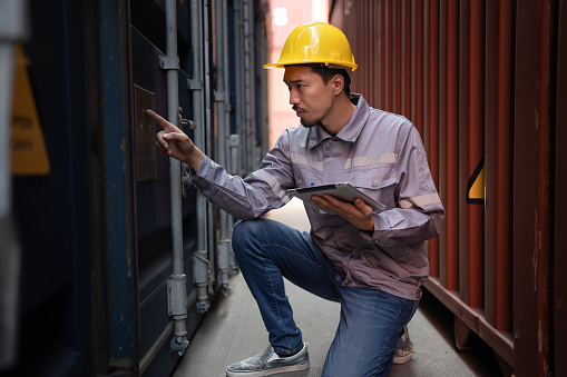 Asia logistic engineer worker or foreman use tablet computer working at container site