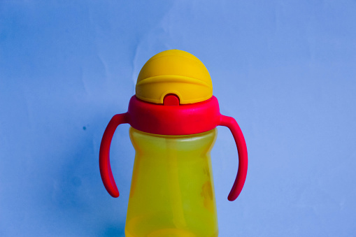 Little red and yellow children's drinking bottle on a blue background