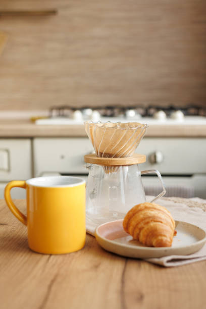 istock makes black coffee in morning kitchen. brews in purover. yellow cup with coffee drip 2050807829
