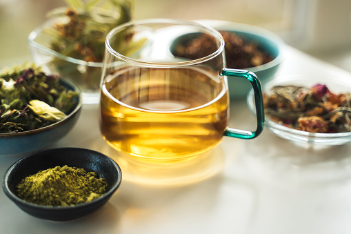 A cup of tea with dry fruit, flowers, and herbs.