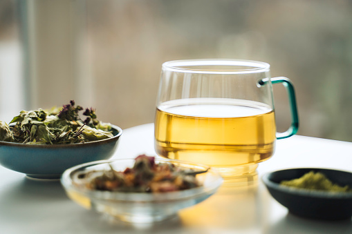 A cup of tea with dry fruit, flowers, and herbs.