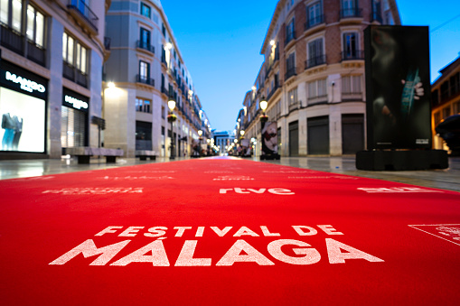 Malaga, Andalusia, Spain - March 1, 2024. A famous street, city promenade, Larios Street in Malaga with the Festival de Málaga logo on the red carpet to promote the annual film festival with movie screenings and an award ceremony in Malaga. City buildings with shops and restaurants line the beautiful walkway, soon to be filled with celebrities, movie stars, actors, actresses, fans and photographers. The famous event is similar to the Oscars and Cannes Film Festival but it features Spanish language films.