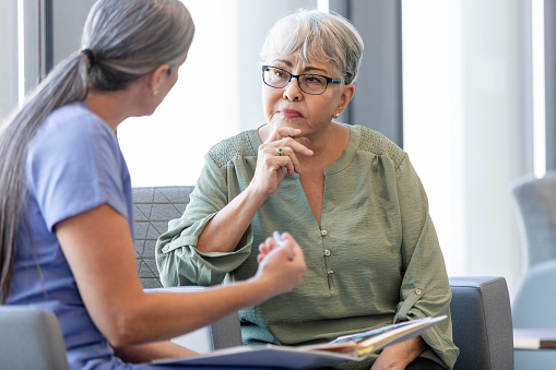 Senior woman listens carefully as female doctor explains diagnosis