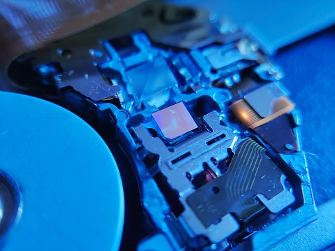 the close-up image of a laptop CD-ROM optic. Illuminated by a soft glow, intricate lenses and sensors come into focus, poised to decode and retrieve digital data stored on compact discs.