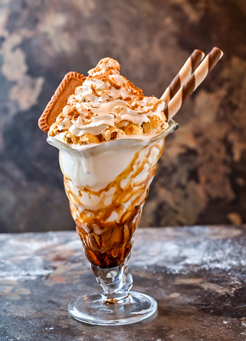 Lotus Biscoff Sundae milkshake with chocolate, whipped cream and straw served in glass isolated on dark background side view of healthy drink