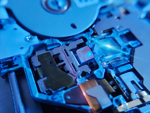 the close-up image of a laptop CD-ROM optic. Illuminated by a soft glow, intricate lenses and sensors come into focus, poised to decode and retrieve digital data stored on compact discs.