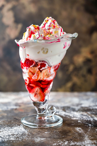 Tutti Fruity Sundae whipped cream shake with banana and strawberry served in glass isolated on dark background side view of healthy drink