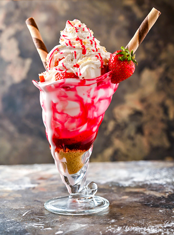 Strawberry Shortcake Sundae shipped cream shake with straw served in glass isolated on dark background side view of healthy drink