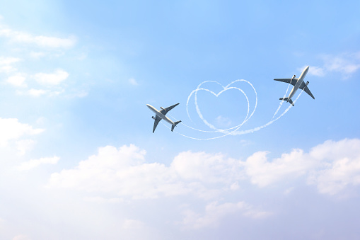 Horizontal nature background with two aircrafts drawing a heart in the sky. Flight route of aircraft in shape of a heart. The concept of the love of travelling