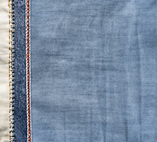 istock Blue and light grey denim background with a red seam. Light blue color denim jeans fabric texture with decorative border. Copy space for text 2051011852