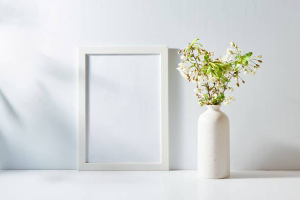 istock Mockup with a white frame and spring flowers in a vase on a light background. Empty poster frame mockup for presentation design, text, lettering 2051027519