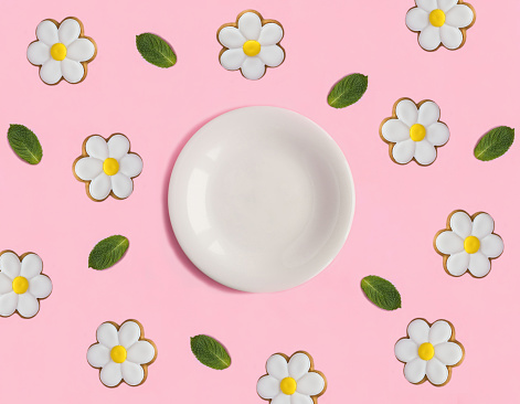 Empty white plate for text and gingerbread cookies in the shape of a daisy on the pink background. Top view. Copy space. Close-up.
