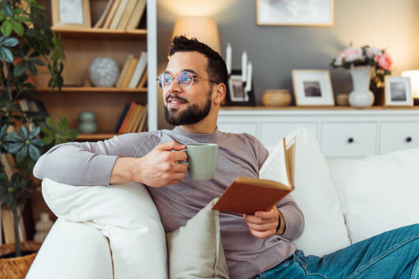 istock Handsome man reading a book in his living room 2051060899