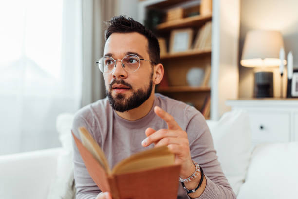 istock Handsome man reading a book in his living room 2051061438