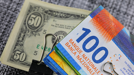 Several Swiss franc and US dollar banknotes folded in half. These can be used to illustrate a wide range of financial topics.