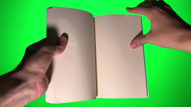 Leafing through a book with white pages on a green chroma key background