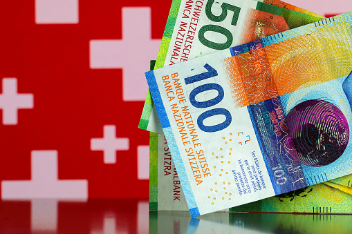 This is Swiss paper money. Some banknotes are shown against a background of Swiss flag symbols. This theme can be used to illustrate many different financial topics.