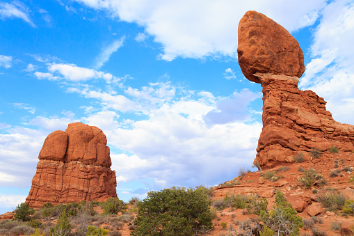 Two balanced desert rocks under a cloudy blue sky