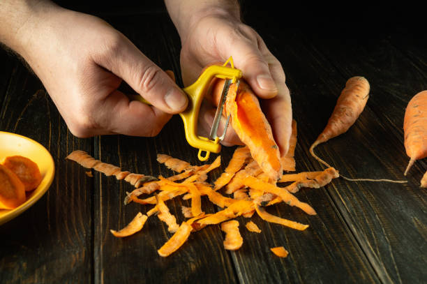 istock Chef hands peel carrots with a vegetable peeler on the kitchen table in a restaurant. Preparing a vegetable dish for breakfast 2051130911