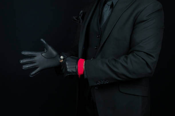 istock Stylish Gangster in Black Suit Pulling on Leather Gloves 2051165845