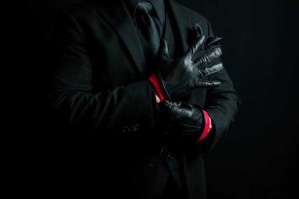 istock Stylish Gangster in Black Suit Pulling on Leather Gloves 2051165858