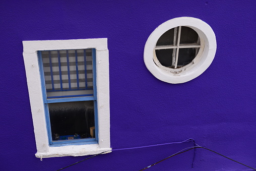 Bright Purple Wall With White-Trimmed Window in the Daylight