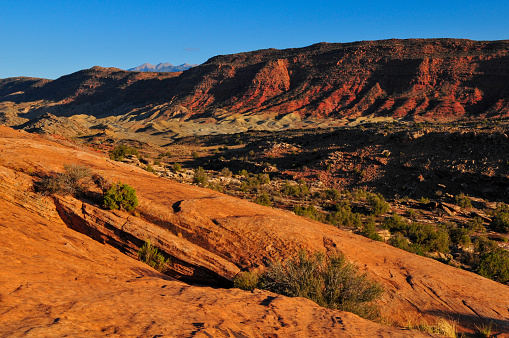 Rugged, barren hills and the La Sal mountains on the way to the Delicate Arch, Arches National Park, Moab, Utah, USA.