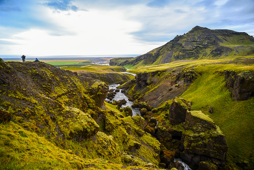 Hikers admiring the view from the rim of the waterfall-lined Skógá River canyon, on the trek from Skógafoss up to the Fimmvörðuháls hut and pass, south Iceland.