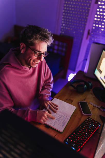 istock Young student in pink sweatshirt and glasses having fun reading her notebook in the room 2051291490