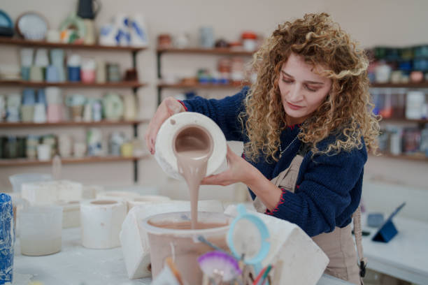 istock Woman making ceramic pots in the ceramic workshop, pouring clay into the molds. 2051304850