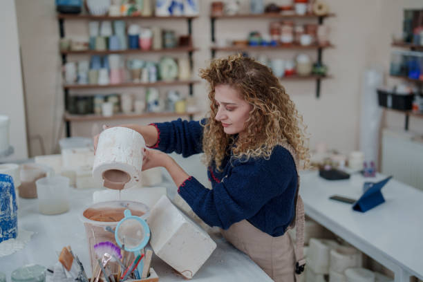 istock Woman making ceramic pots in the ceramic workshop, pouring clay into the molds. 2051308528