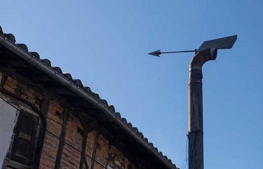 Domestic wind directional chimney cap equipped with arrow. Blue sky background