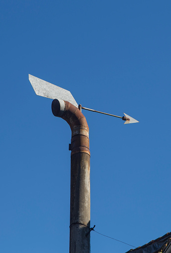 Domestic wind directional chimney cap equipped with arrow. Blue sky background