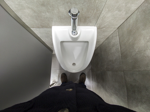 Mature man in front of a urinal. Overhead view