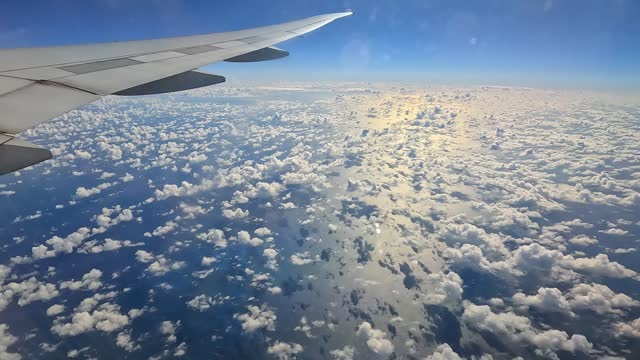 Aerial view of fluffy cumulus clouds from airplane window during daytime flight