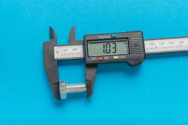 Measuring a metal bolt with an electronic vernier caliper on a blue background. A tool for accurate measurement of dimensions.