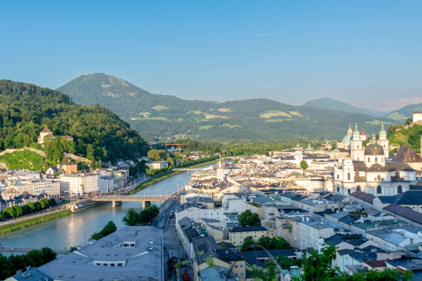 Panoramic View of Salzburg Cityscape with Alpine Backdrop in Sunset Salzburg, Salzburg - Austria - 06-17-2021: Salzburg skyline with Salzach River, historic architecture, and lush Kapuzinerberg hill under the alpine horizon Kapuzinerberg stock pictures, royalty-free photos & images