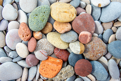 Diverse river stones in multiple colors and sizes, tightly packed together