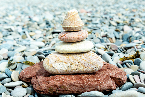 A carefully balanced stack of smooth stones creates a sense of Zen against a pebbled beach backdrop