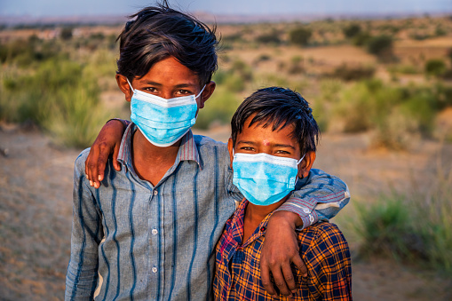 Two Indian young boys wearing face masks - desert village, Thar Desert, Rajasthan, India.