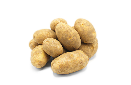 A pile of whole russet Idaho potatoes potato tuber fresh from the ground unwashed still dirty isolated on white background