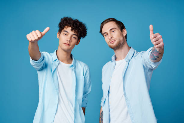 istock young guys in the same shirts and t-shirts are gesturing with their hands on a blue background friends 2051476148
