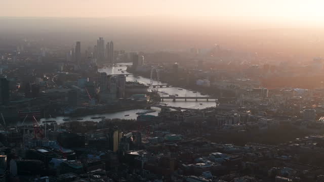 Tight aerial shot looking towards the London eye and houses of parliament on the Thames at sunset