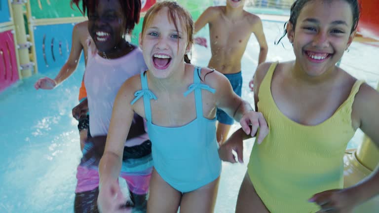 Children at water park running thru falling water