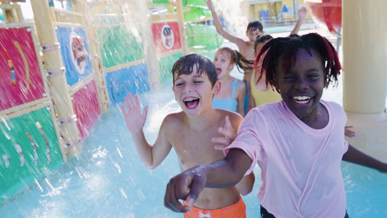 Children at water park run by water slides in play area