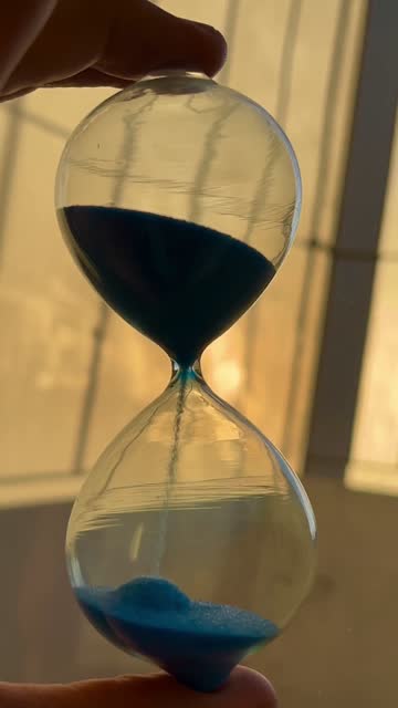 A hand holding an hourglass that represents time passing